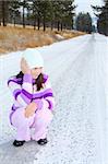 Brunette girl sitting on snow covered road