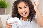 Beautiful young happy mixed race interracial African American girl child celebrating playing video games