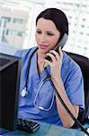 Portrait of a female doctor on the phone while using a monitor in her office