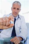 Portrait of a doctor showing a pill in his office