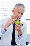 Portrait of a doctor putting his stethoscope on an apple in his office
