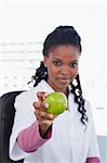 Portrait of a female doctor showing an apple in her office