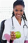Portrait of a smiling female doctor showing an apple in her office