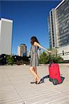 brunette woman with red suitcase walking in Madrid city Spain