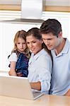 Portrait of a family using a laptop in their kitchen