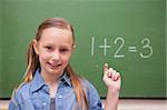 Schoolgirl raising her hand in front of a blackboard