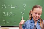 Schoolgirl with the thumb up in front of a blackboard