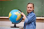 Smiling schoolgirl looking at a globe in a classroom