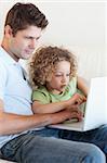 Portrait of a young boy and his father using a laptop in their living room