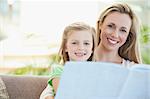 Mother and daughter reading together on the sofa