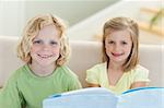 Siblings reading booklet together on the sofa