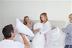Family having a pillow fight together in the bedroom