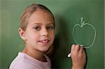 Schoolgirl drawing an apple on a blackboard