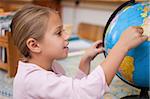 Smiling schoolgirl pointing at a country on a globe