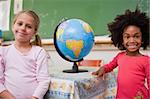 Schoolgirls posing with a globe in a classroom