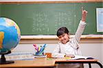 Schoolgirl raising her hand to answer a question in a classroom