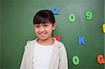 Happy schoolgirl posing in front of a blackboard in a classroom