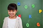 Smiling schoolgirl posing in front of a blackboard in a classroom