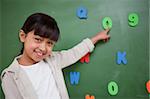 Schoolgirl pointing at a letter on a blackboard