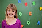 Little schoolgirl posing in front of a blackboard in a classroom