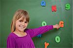 Little schoolgirl pointing at a letter in a classroom