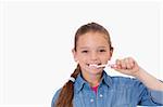Healthy girl brushing her teeth against a white background
