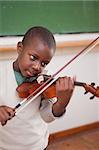 Portrait of a schoolboy playing the violin in a classroom