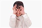 Girl putting her fingers around her eyes against a white background