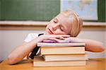 Girl sleeping on her books in a classroom
