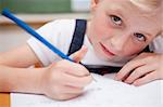 Close up of a serious schoolgirl writing something in a classroom