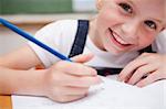 Close up of a smiling schoolgirl writing something in a classroom