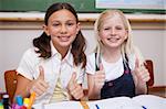 Portrait of happy pupils working together with the thumbs up in a classroom