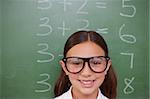 Smart schoolgirl posing in front of a blackboard