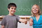 Happy pupils posing with the thumb up in a classroom