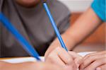 Close up of two arms holding pens in a classroom