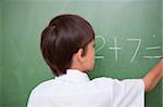 Little schoolboy writing an addition on a chalkboard