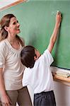 Portrait of a schoolteacher helping a schoolboy doing an addition on a blackboard