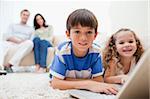 Cute kids playing computer games on laptop together