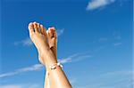 Women's beautiful legs on the beach against sky