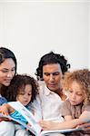 Young family on the couch looking at photo album together