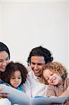 Cheerful young family on the sofa looking at photo album together