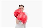 Businesswoman wearing boxing gloves against a white background