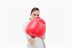 Serious businesswoman boxing against a white background