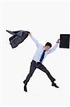 Businessman jumping while holding his jacket and a briefcase against a white background