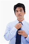 Portrait of a businessman fixing his tie against a white background