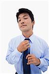 Portrait of a relaxed businessman fixing his tie against a white background