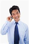 Portrait of a smiling businessman making a phone call against a white background