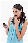 Portrait of a surprised woman reading a text message against a white background