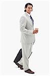 Side view of businessman with coffee and wheely bag against a white background