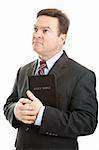 Religious Christian man in a business suit, holding his bible and looking heavenward.  Isolated on white.